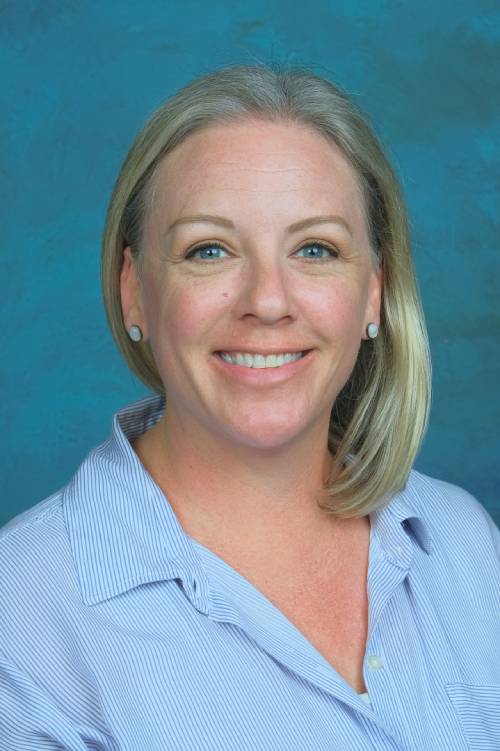 Smiling woman in professional attire representing RSM Christian School, emphasizing education and campus community.